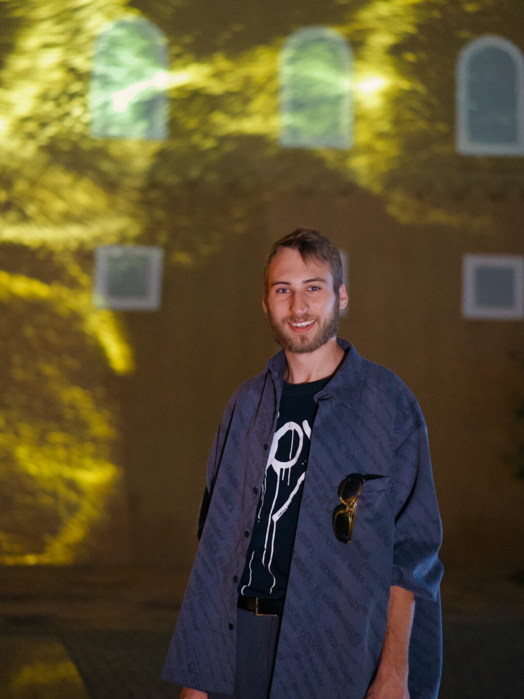Fran Brišar in front of a projected light installation on a stone façade.